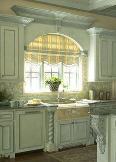 Arched windows over sink with roman shade and molding connecting .