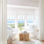 Coastal seating area in the lving room decorated in all white .