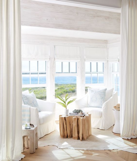 Coastal seating area in the lving room decorated in all white .