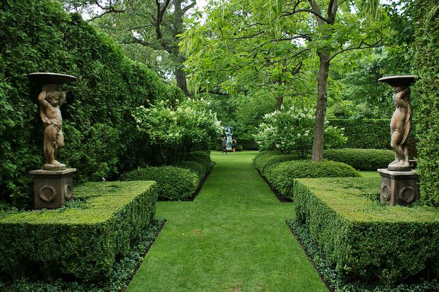 Formal hedges and garden statuary in one of the front gardens .